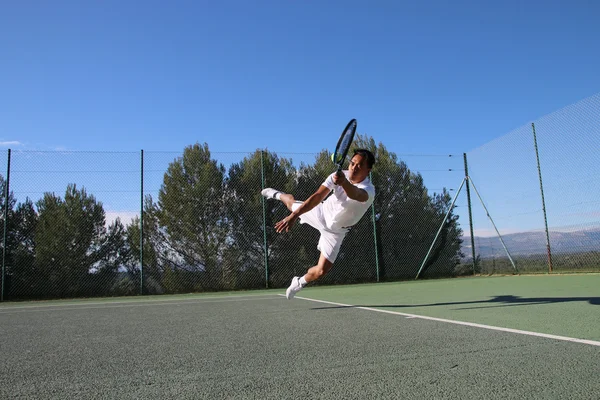 Tennis player dives to catch a ball — Stock Photo, Image