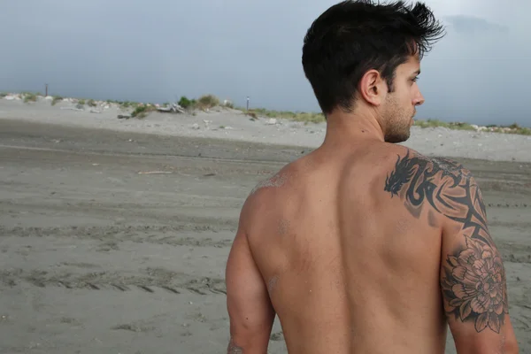 Macho tatuado en la arena — Foto de Stock