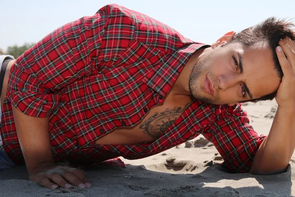 Handsome male lying on the sand — Stock Photo, Image