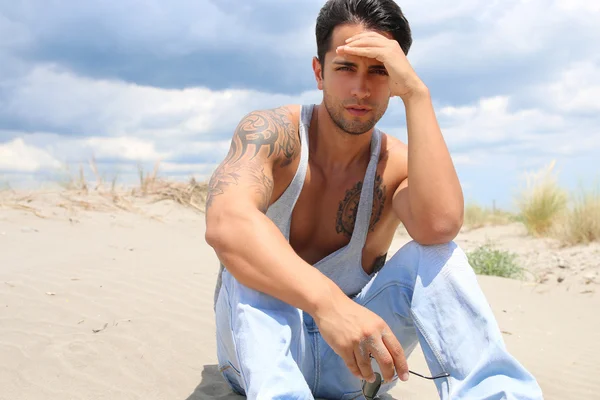 Handsome man sitting on the sand — Zdjęcie stockowe