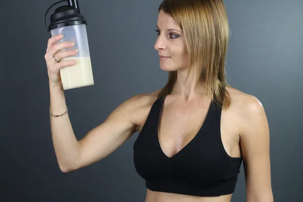 Beautiful woman looking a protein shaker — Stock Photo, Image