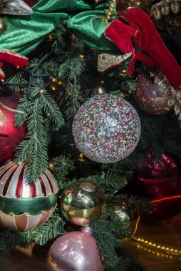 A close-up of a Christmas tree ball against the backdrop of a New Years tree
