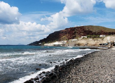 Santorini adasında, siyah çakıl taşları ve bir dağ olan sakin bir deniz, Yunanistan