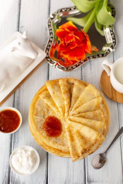 Reçelli krep, kahvaltı, çiçek, bahar, kadınlar günü. Geleneksel Rus blini beyaz ahşap masada. Krep haftası. Shrovetide. Bölgesel yiyecekler. Kapatın. Dikey biçim.