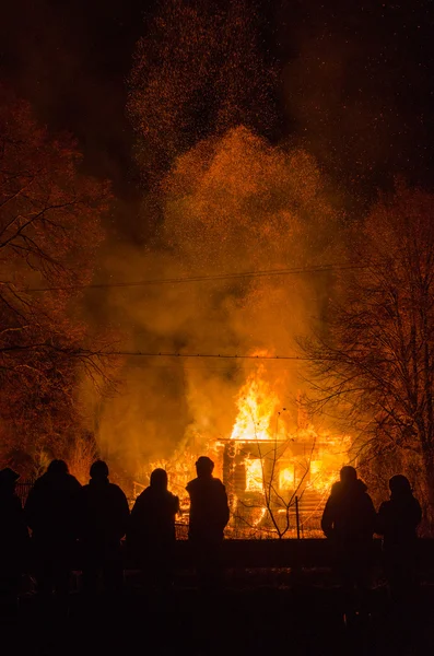 Ludzie na tle płonącego domu — Zdjęcie stockowe