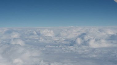 Yumuşak beyaz bulutların üzerinde berrak mavi bir gökyüzünün altında ufka uzanan sakin bir hava manzarası. Pürüzsüz ve huzurlu görüntüler yüksek irtifada, sakin ve minimalist bir atmosfer yaratıyor.