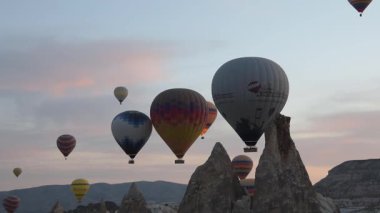 Kapadoki, Türkiye 'de 25 Mayıs 2021 tarihinde Türkiye' nin Kapadokya şehrinde birçok renkli sıcak hava balonu gün doğumunda gökyüzüne yükseliyor, turistler kalkış sürecini izliyor. Kavram