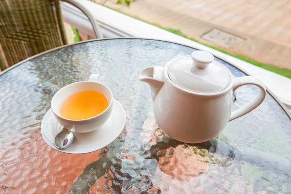 Cup of tea and teapot on glass table — Stock Photo, Image