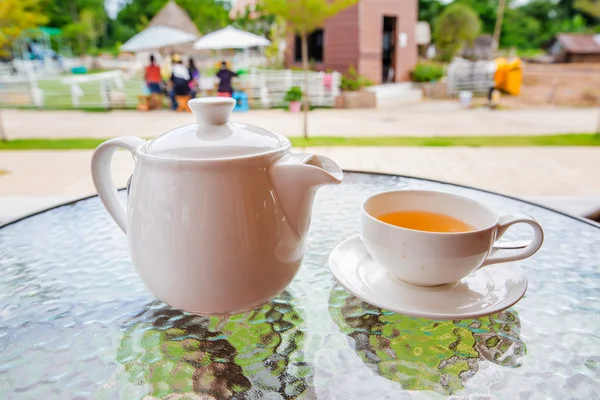 Xícara de chá e bule na mesa de vidro — Fotografia de Stock