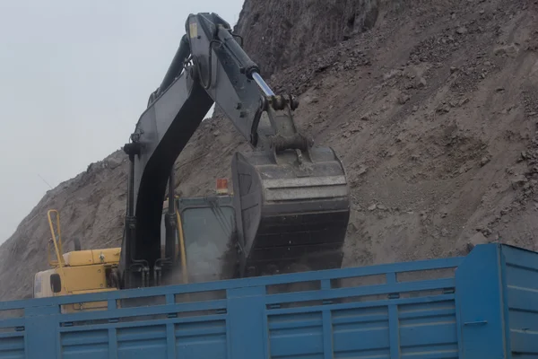 Excavatrice chargeant benne bascule camion benne sur le chantier de construction — Photo