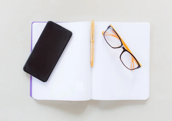 Notebook, caneta, telefone celular e óculos — Fotografia de Stock