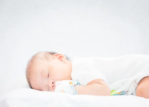 Bambino tranquillo sdraiato su un letto mentre dorme . — Foto Stock