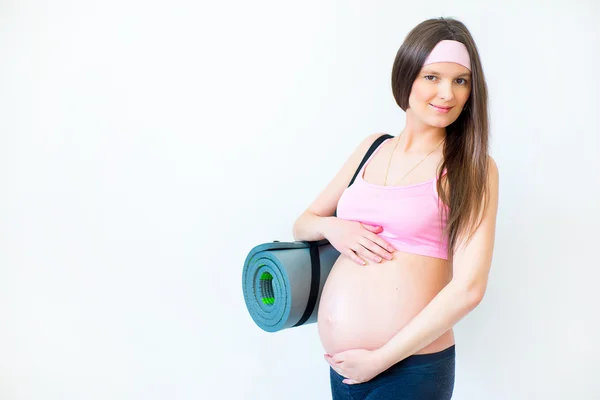 Menina grávida com tapete para a aptidão nas mãos — Fotografia de Stock