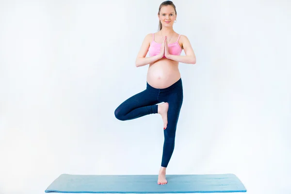 Mujer embarazada de pie sobre una pierna —  Fotos de Stock
