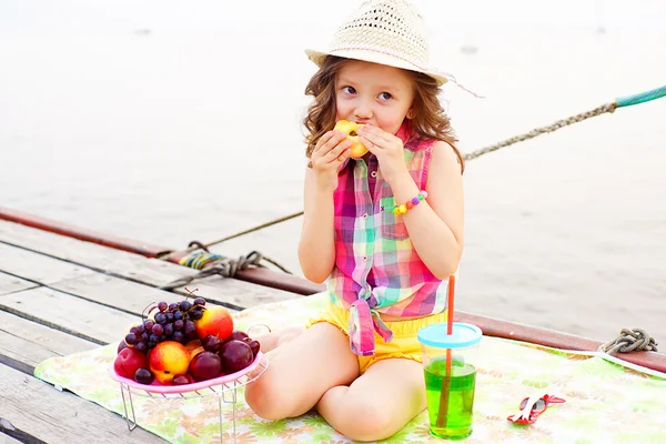 湖の近くの桟橋で桃を食べる少女 — ストック写真