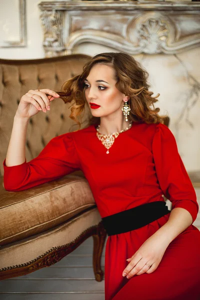 Het meisje in een rode jurk met gouden kostuum juwelen — Stockfoto