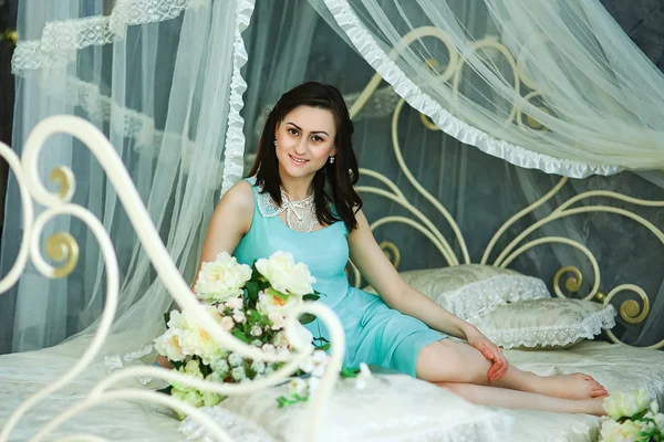 Flickan i en klänning på en säng — Stockfoto