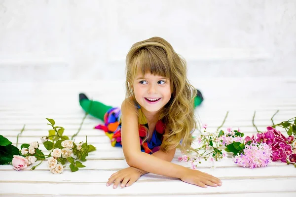 花の近くの小さな女の子ポーズ — ストック写真