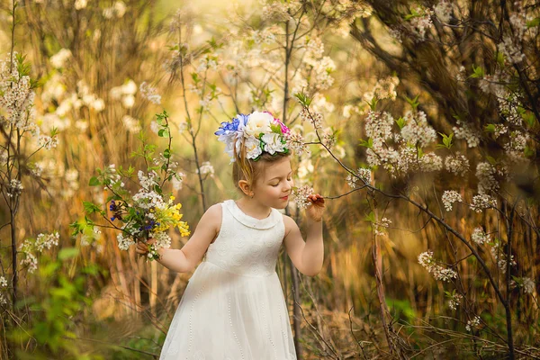 Das kleine Mädchen mit dem Hut aus Blumen im Wald — Stockfoto