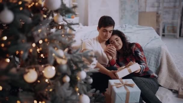 Liefdevol koppel gekleed in de winter truien brengen romantische tijd zitten naast de kerstboom. — Stockvideo