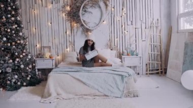 Yatakta oturan güzel bir kızın hediyesini açtığı geniş açı..