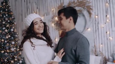 Genç çift güzel dekore edilmiş Noel ağacının yanında kucaklaşıyorlar..