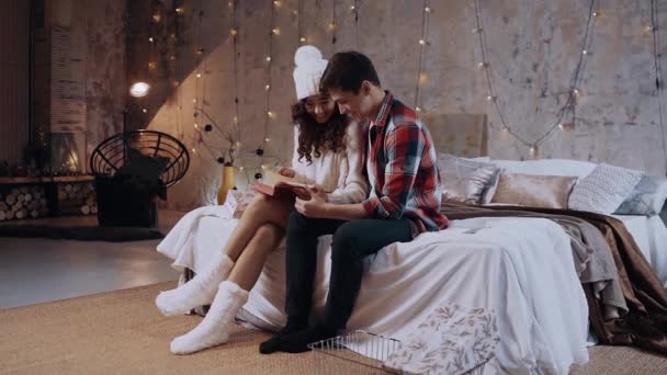Смішні пари розважаються разом, читаючи книгу у вітальні, сидячи на ліжку , — стокове відео