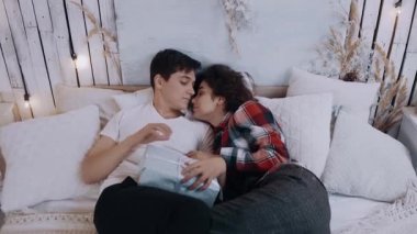 Romantik genç çift Noel arifesinde yatak odasında otururken kucaklaşıyorlar..
