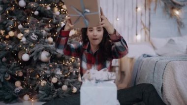 Son hediyeyi Noel ağacının yanına koyan komik bir genç kadının portresi.