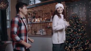 Çocuksuz iki genç, yavaş bir hızla filme çekiliyor, zıplıyor ve ışıklarla süslenmiş ağacın yanında el sıkışıyor..