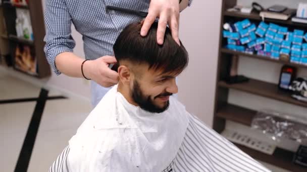 A businessman came to a beauty salon. He wants a new change. The miller cuts them with a hair clipper. It is a wonderful result. The customer is satisfied. — Stock Video