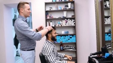 Berber dükkanının içiyle ilgilenen genç bir adam. Berber işini yeni bitirdi ve ona işini bitirmiş olanı gösterdi. Müşteri çok memnun.