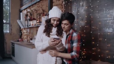 Akıllı telefon kullanan genç bir çift ailesiyle konuşuyor. Mutlu Noeller.
