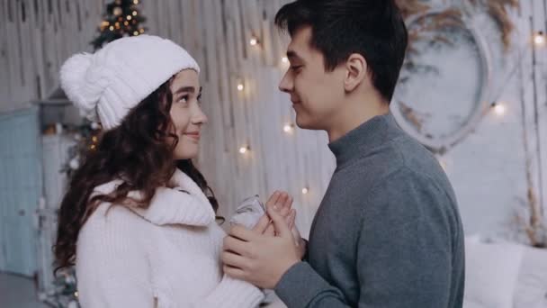 Jonge man biedt een geschenk aan zijn vriendin thuis in de woonkamer — Stockvideo