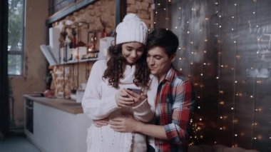 Akıllı telefon kullanan genç bir çift ailesiyle konuşuyor. Mutlu Noeller.