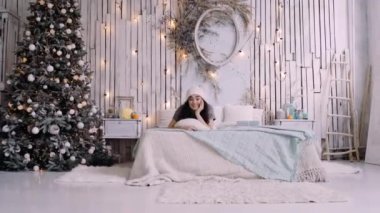 Yatağında şapkası olan, kışlık giysili mutlu genç bayan..