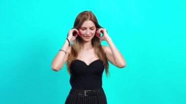Genç kız parmaklarını kulaklarına koyar ve müzik çalar..