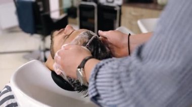 Saç bakımı sırasında gevşemiş bir müşteri. Yakışıklı genç.