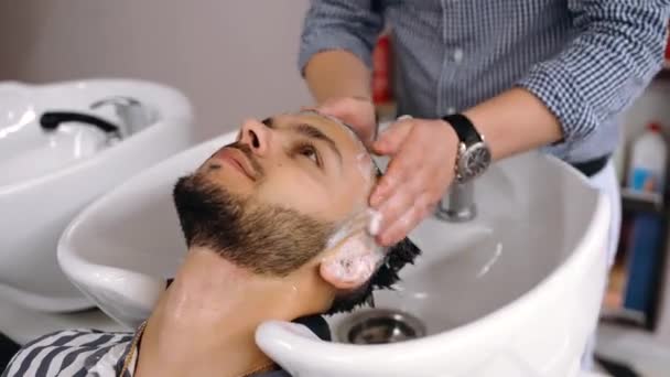 흐르는 물 속에서 고객의 머리를 깨끗하게 하는 장인의 손으로 가까이 다가가는 모습. — 비디오