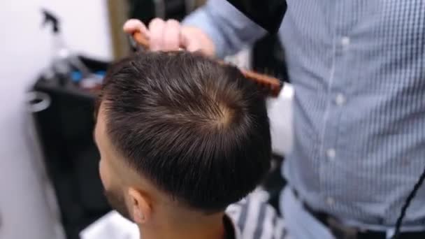 Close-up em que o barbeiro seca um cabelo de clientes. — Vídeo de Stock