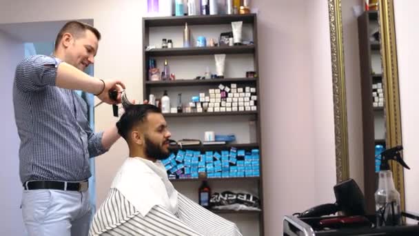 Un jeune homme impressionné par le travail d'un coiffeur sourit. — Video