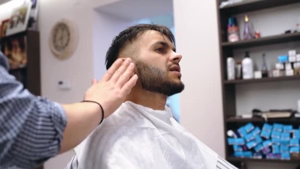 Перукар влаштовує клієнтам бороду, бородатого чоловіка, масажує шкіру обличчя . — стокове відео