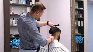 Berber dükkanı müşterileri üzerinde çalışıyor. Dört adam iş gününün tadını çıkarıyor.