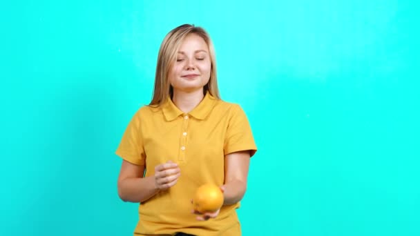 Молодая женщина держит в руках апельсин и пропагандирует здоровый образ жизни. — стоковое видео