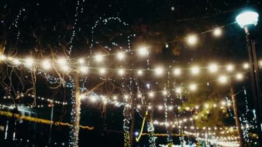 Şehir muhteşem bir şekilde Noel için dekore edilmiş. Dışarıda kar yağarken ışıklar parlıyor..