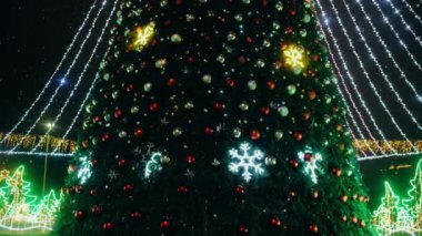 Dışarıda kar yağarken büyük renkli kürelerle süslenmiş Noel ağacı..