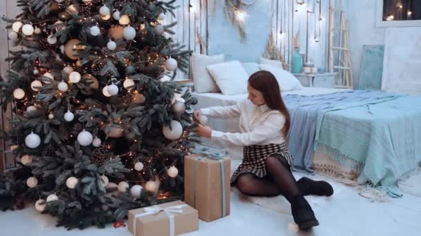 La chica feliz sonríe de par en par después de haber terminado de decorar el árbol de Navidad. — Vídeo de stock
