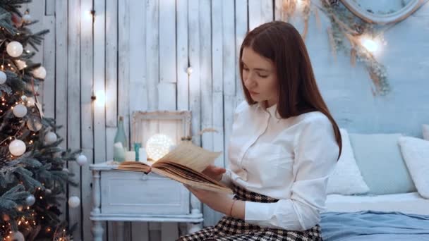 Le portrait d'une belle jeune femme qui lit avec enthousiasme à la maison pour Noël — Video