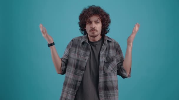 A zavarodott fiatal hipszter felemeli mindkét kezét. Egy fiatalember pólóban és pólóban. — Stock videók