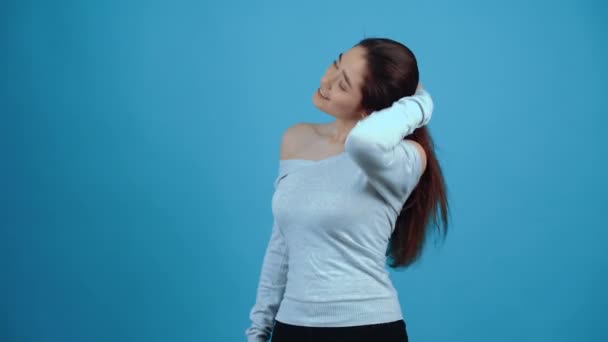 Šťastná mladá žena, usmívající se při aranžování si vlasy — Stock video